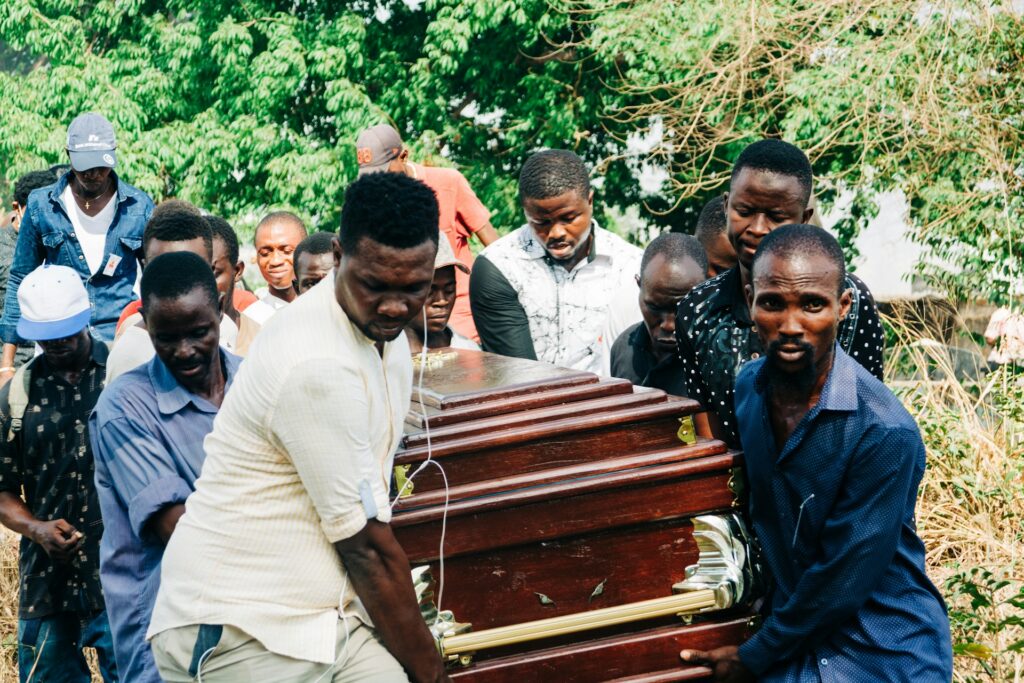 a group of people standing around a wooden casket
