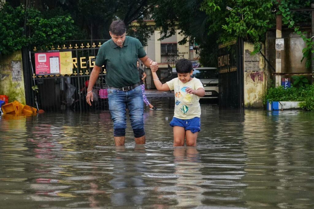 a man and a little girl walking through a flooded street
