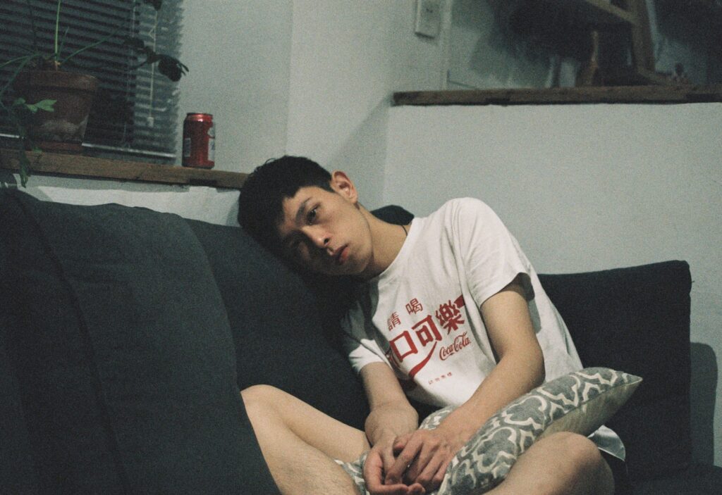man in white T-shirt sitting on black couch
