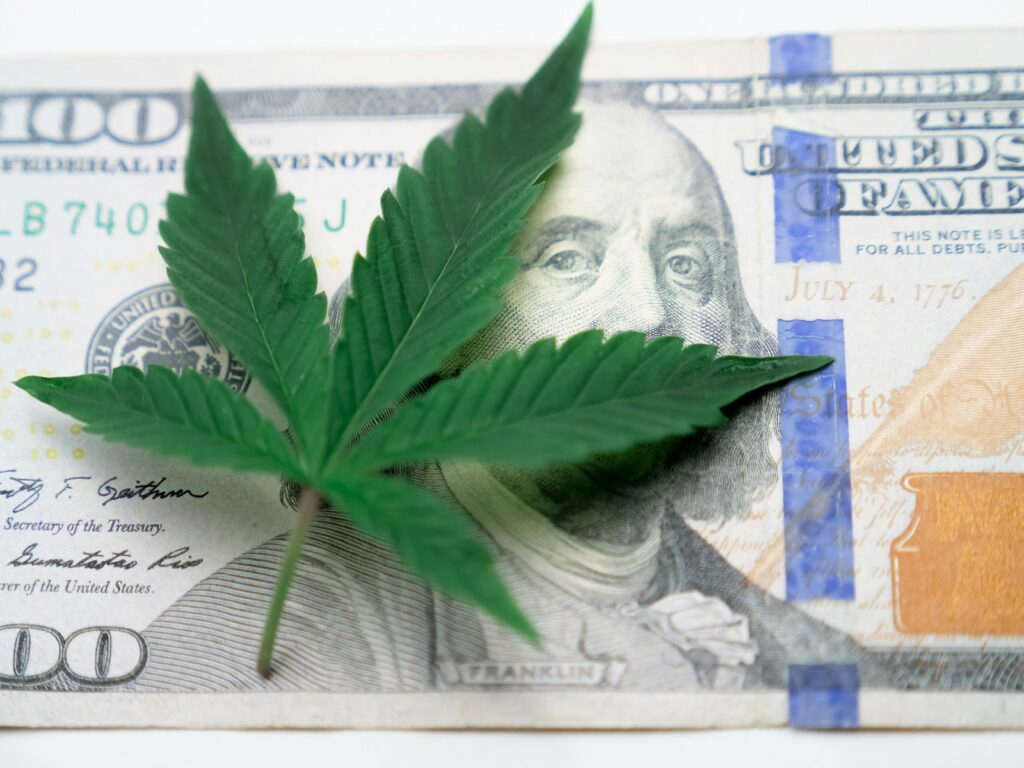 Cannabis leaf placed over a $100 bill showing the financial considerations of marijuana rescheduling.