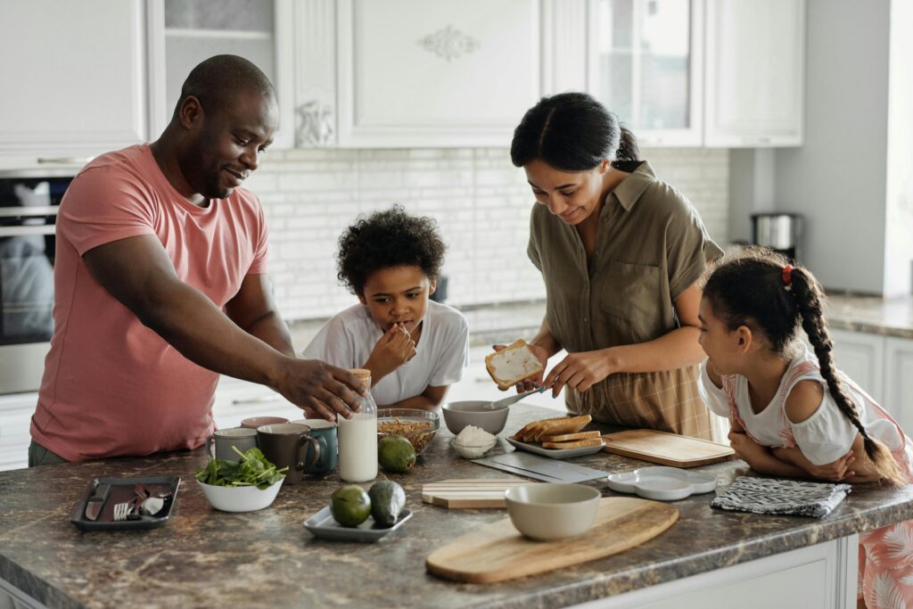 Parents sharing kitchen duties with children, illustrating research on combating low birth rates through shared parental responsibility.