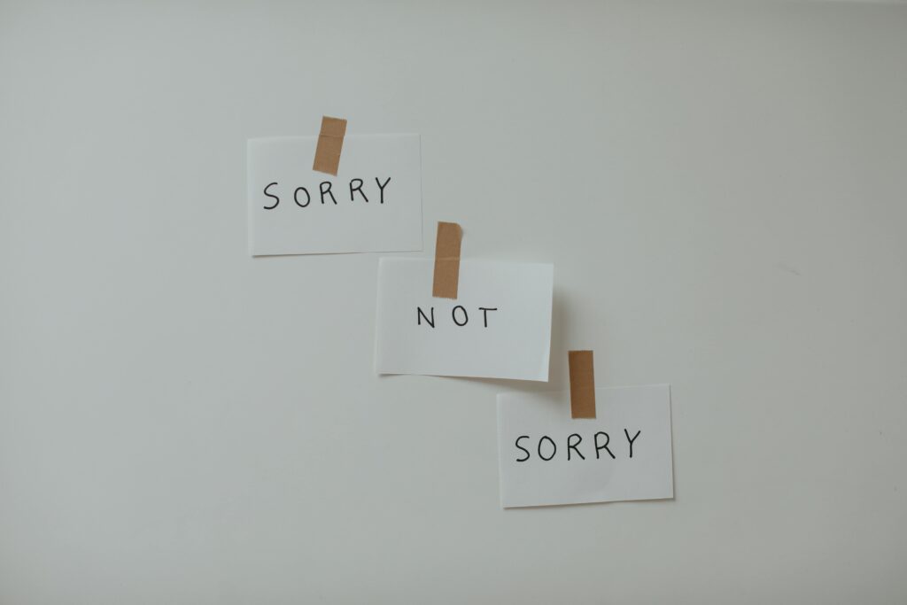 Three white note cards taped to wall reading "SORRY," "NOT," and "SORRY" in sequence.