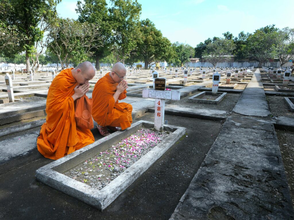 Buddha monk pray in Indonesian cemetery