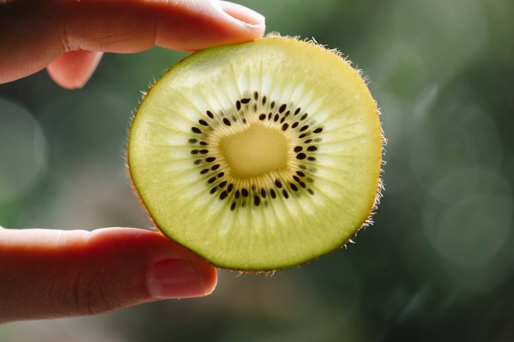 Person showing slice of ripe kiwi