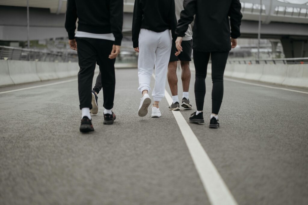 People in Their Activewear Walking on an Asphalt Road
