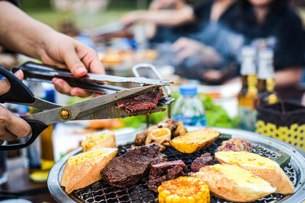 Man Cutting Beef with Scissors Over a Barbecue
