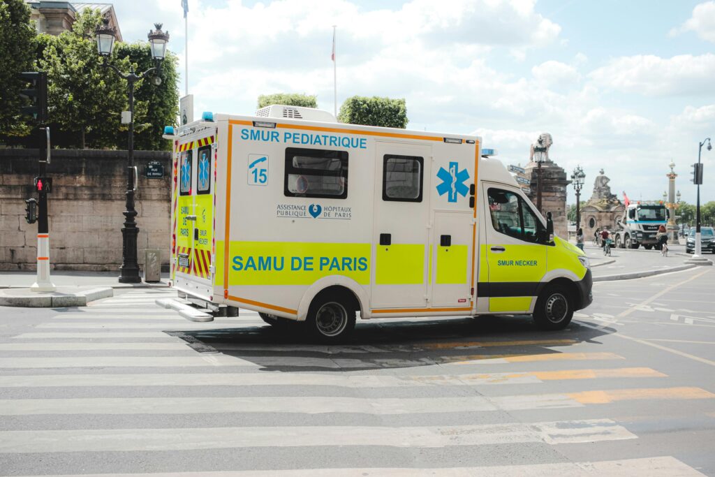 Ambulance driving along road in sunny city
