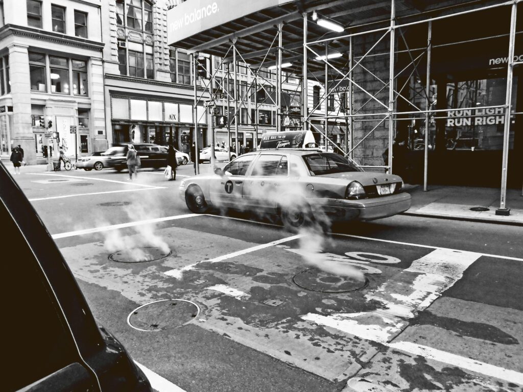 Black and White Photo of Cars and Pedestrians in a City
