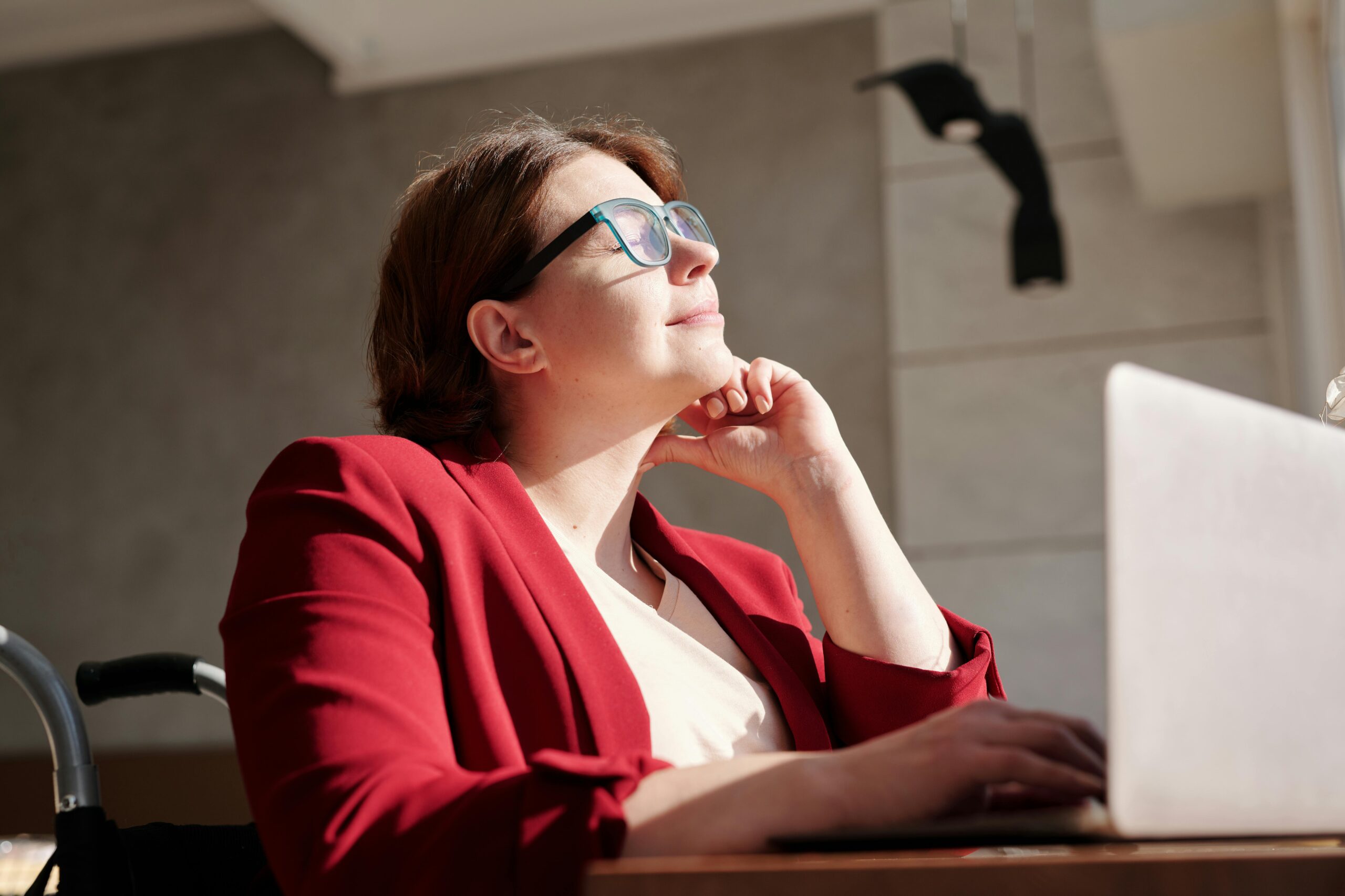 A woman in a red blazer wearing blue eyeglasses with blue laces