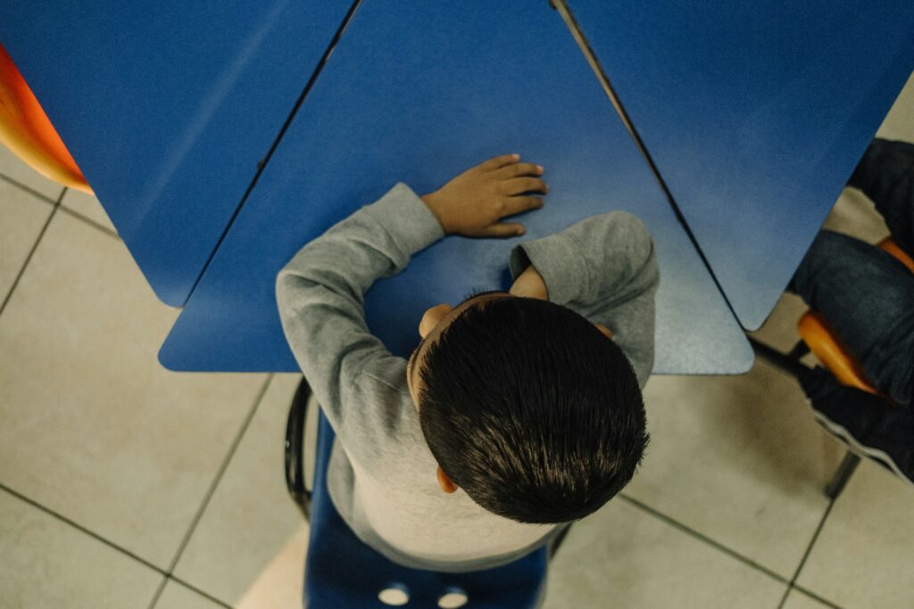 A young boy sitting on a stool holding an umbrella
