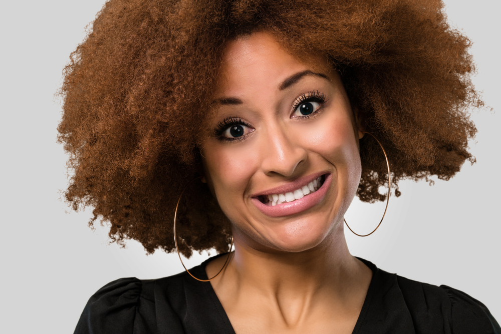 afro woman face closeup fake smiling