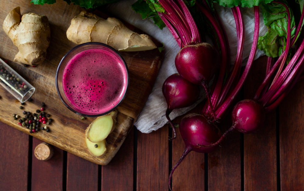 Fresh spicy beetroot juice with Ginger on wooden table, flat lay