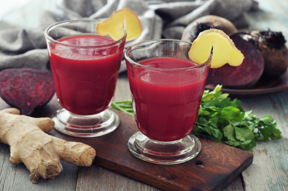 Beetroot smoothie in glass with ginger and  fresh vegetables on wooden background