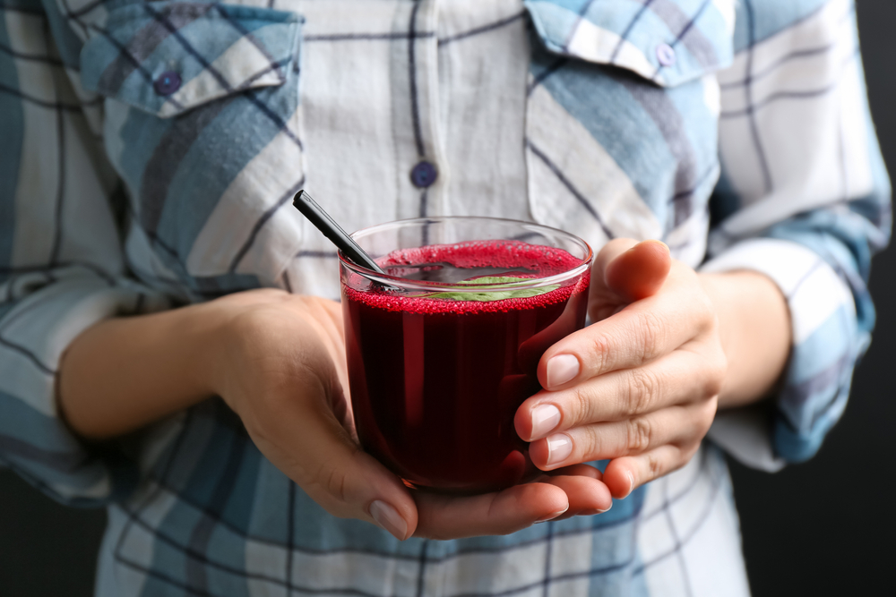 Woman with glass of fresh beet juice, closeup