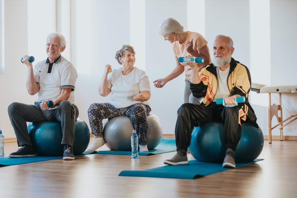 Group of senior people exercising pilates with dummbells sitting on balls