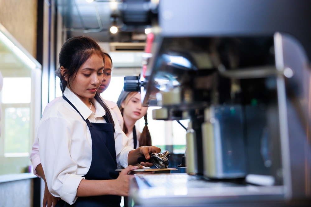 Barista learning make coffee by espresso machine. Group schoolgirl studying hard to learn how to make espresso coffee at barista school.