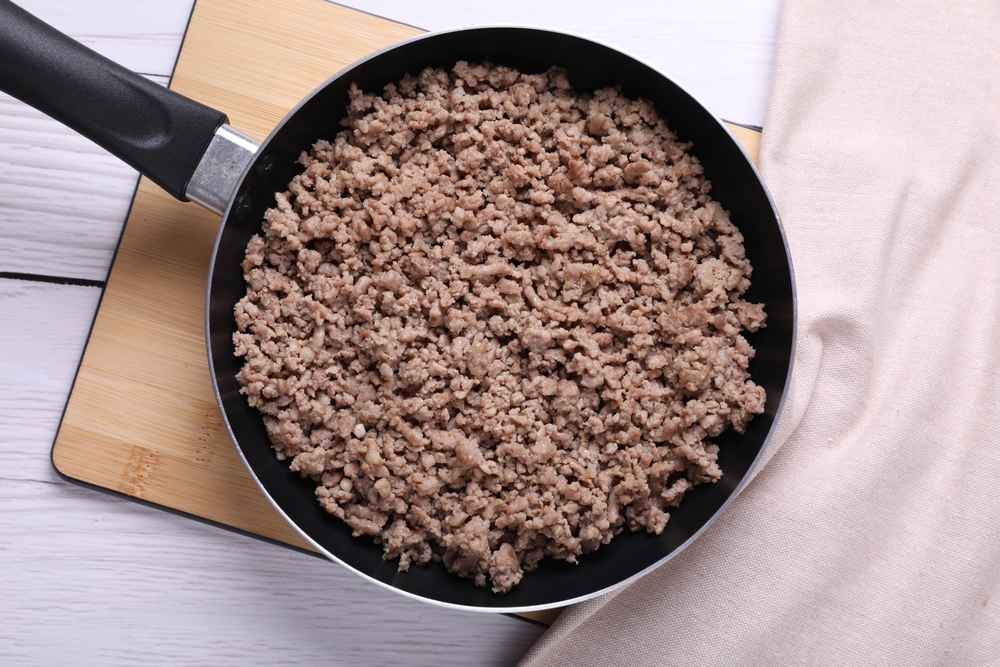 Fried minced meat in pan on white wooden table, top view