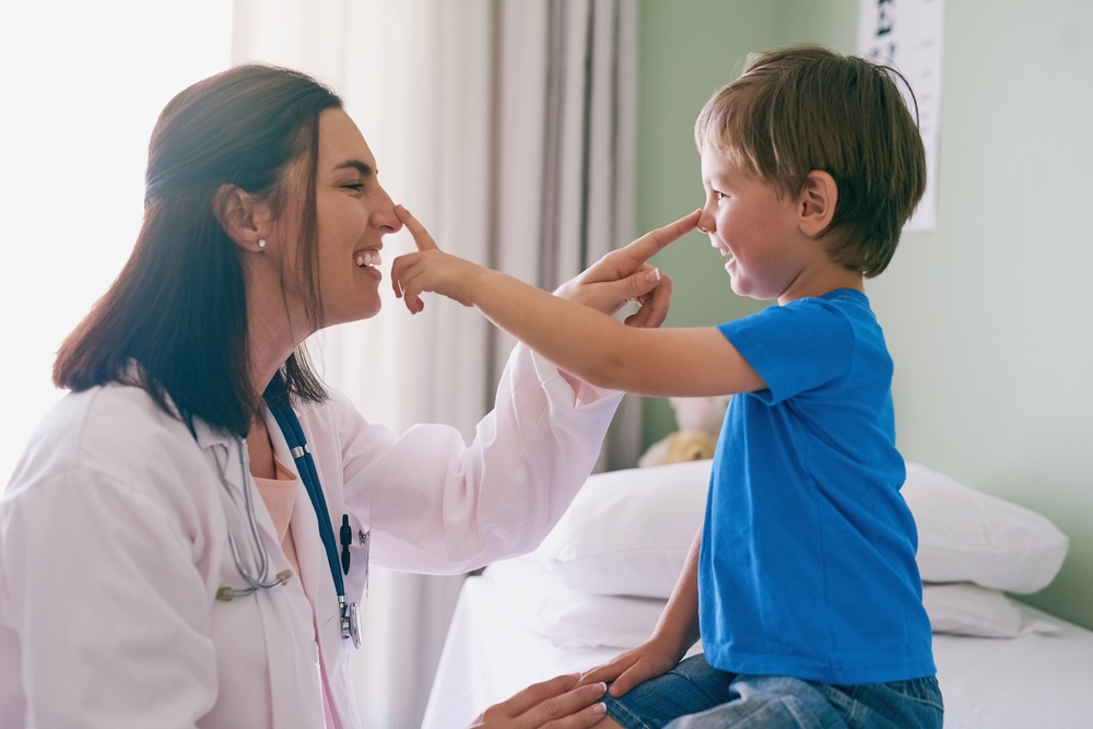 Woman doctor, playing and child at a hospital for healthcare and medical consultation. Fun, nose poke and pediatrician working with a laugh and happiness in a clinic with boy patient with exam