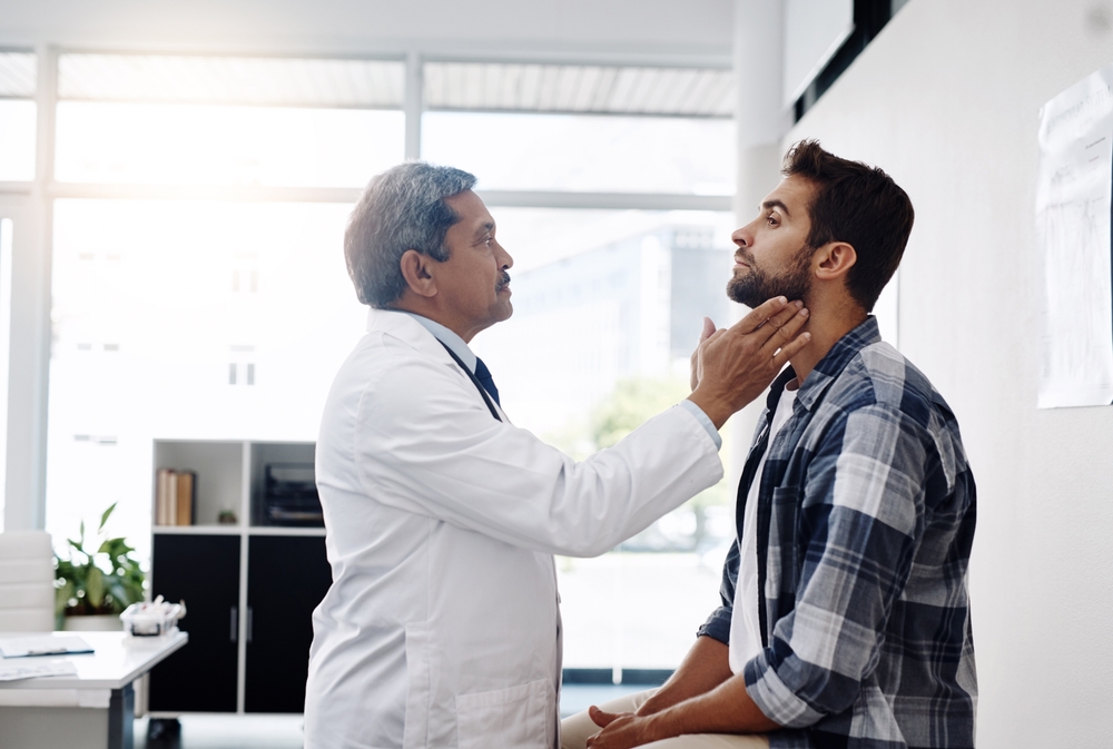 Healthcare, consultation and doctor checking throat of patient with advice, help and solution. Medicine, health care and Indian man with neck pain in doctors office consulting medical professional.