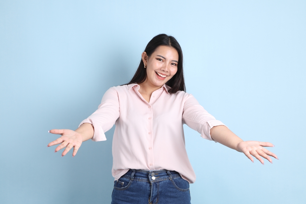 The Asian woman in casual clothes standing on the blue background.