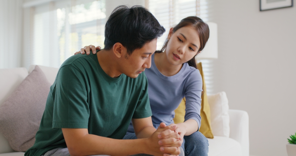 Asia young people stress relief trust talk share suffer cancer pain sick family loss bad news crisis. Sorrow cry man and carer woman sit at sofa home help listen by love hold hand warm hug touch wife.