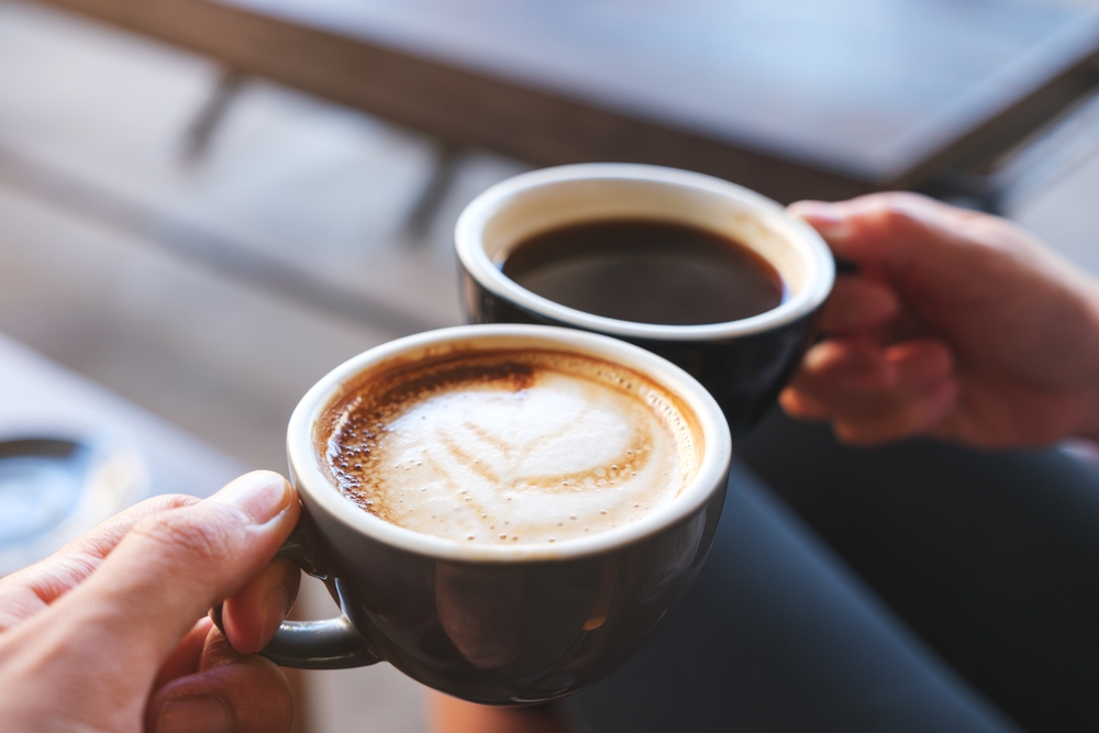 Close-up of man and woman crying over coffee mugs in cafe