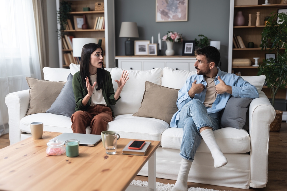 Young married couple husband and wife sitting at home having problems in their marriage and a cold relationship. A boyfriend and a girlfriend roommates have an argument about spending too much money