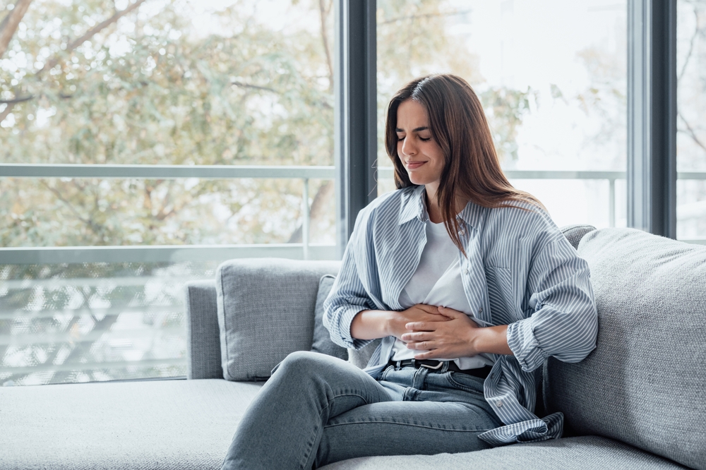 Sick young woman in pain holding belly stomach feeling hurt abdomen ache gastritis pancreatitis symptoms or diarrhea, upset teen girl suffering from indigestion flatulence abdominal problem concept