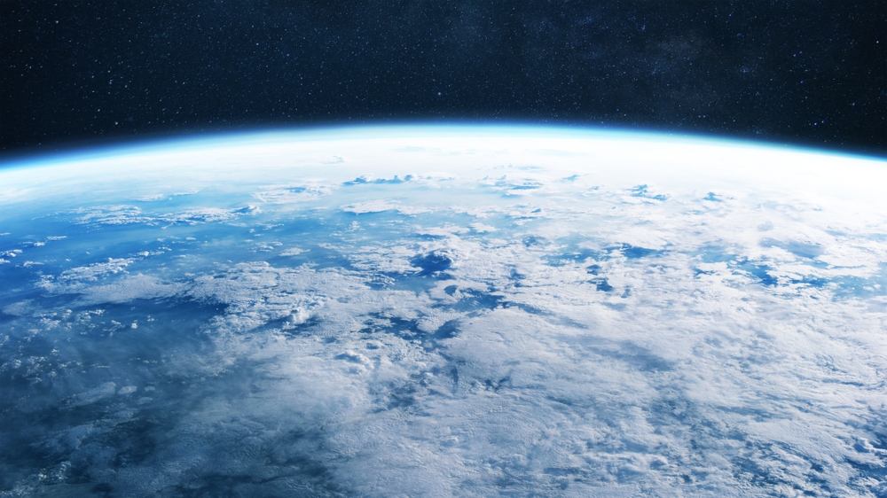 Amazing blue planet earth with ocean, clouds and continents in open space on the starry sky.