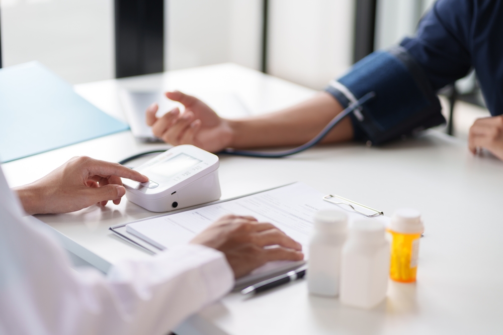 A doctor taking a patient's blood pressure. The patient's arm is equipped with a blood pressure cuff, and the doctor uses the blood pressure.