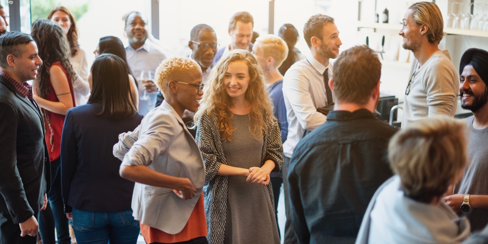 Diverse group of people socializing at a casual gathering. Men and women of various ethnicities engaged in conversation, enjoying a lively social event. Diverse people mingle at a social event.