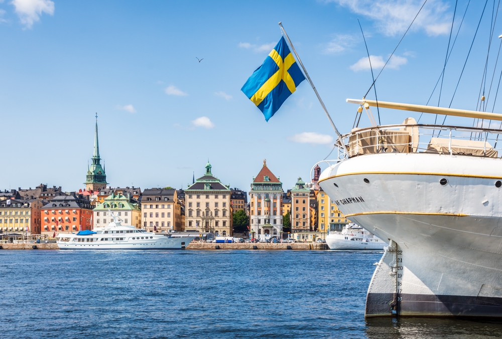 Stockholm, Sweden - August 2, 2024: A swedish flag flies at the stern of the af Chapman sailing ship serving as a youth hostel on the Skeppsholmen islet, opposite Gamla Stan waterfront.