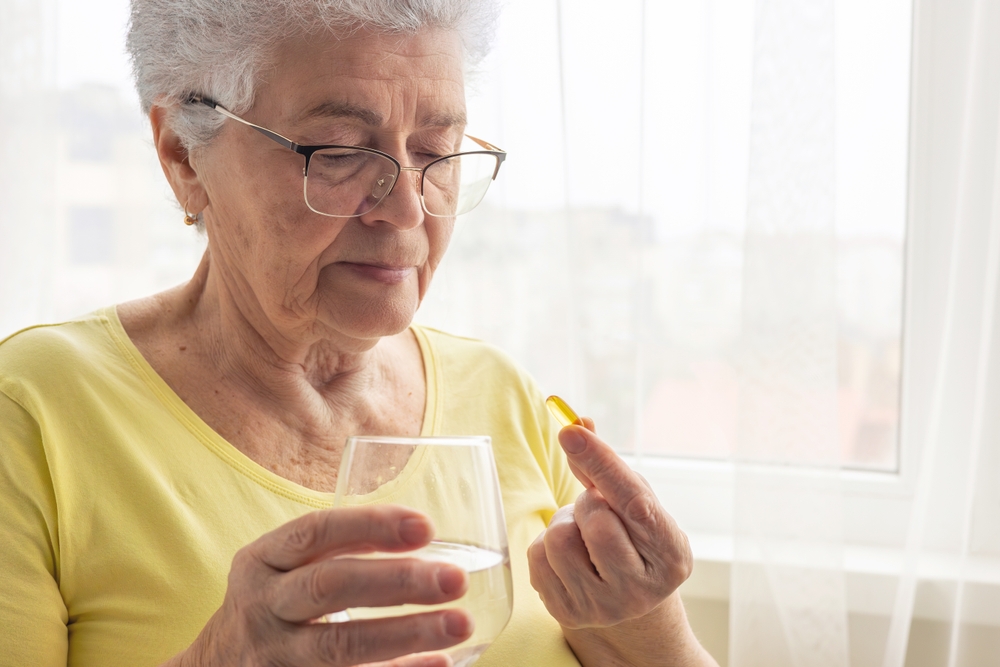 Elderly Woman Taking a Health Capsule. omega 3. Health in adulthood, maintaining activity and energy. Disease prevention, use of vitamins and supplements, treatment, pharmaceuticals. Copyspace