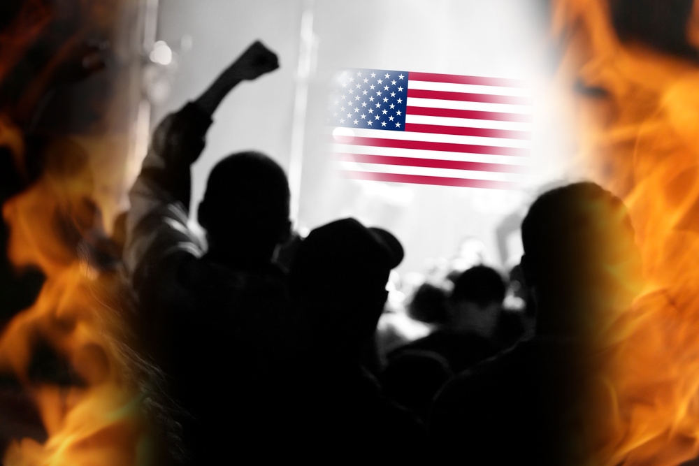 Crowd of passionate protesters gathered under the USA flag, expressing opposition to the Trump administration and defending democracy and the Constitution. Symbolic scene reflecting political tension.