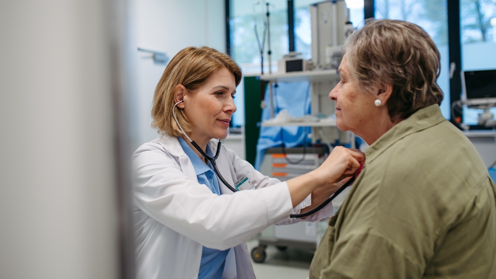 Geriatrician listening to senior patient's heartbeat.