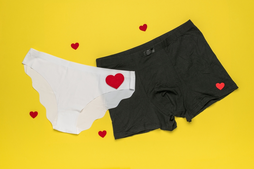 Romantic Underwear Couple: Black Boxers and White Panties with Red Hearts on Yellow Background