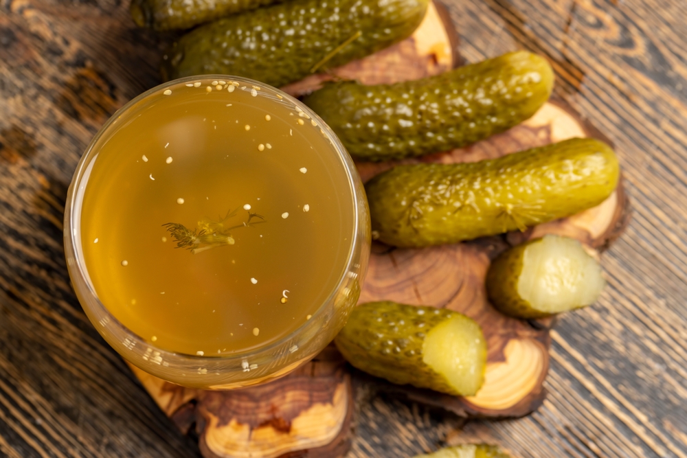 pickled cucumbers and pickled ripe cucumbers next to a glass, poured pickle with spices and whole crispy cucumbers on a board, close up