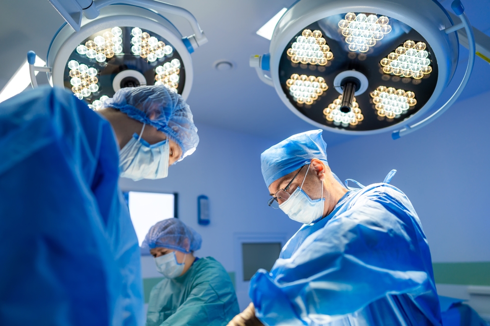 Surgical team at hospital. Medical professionals work diligently in an operating room, focused on a patient under bright surgical lights.