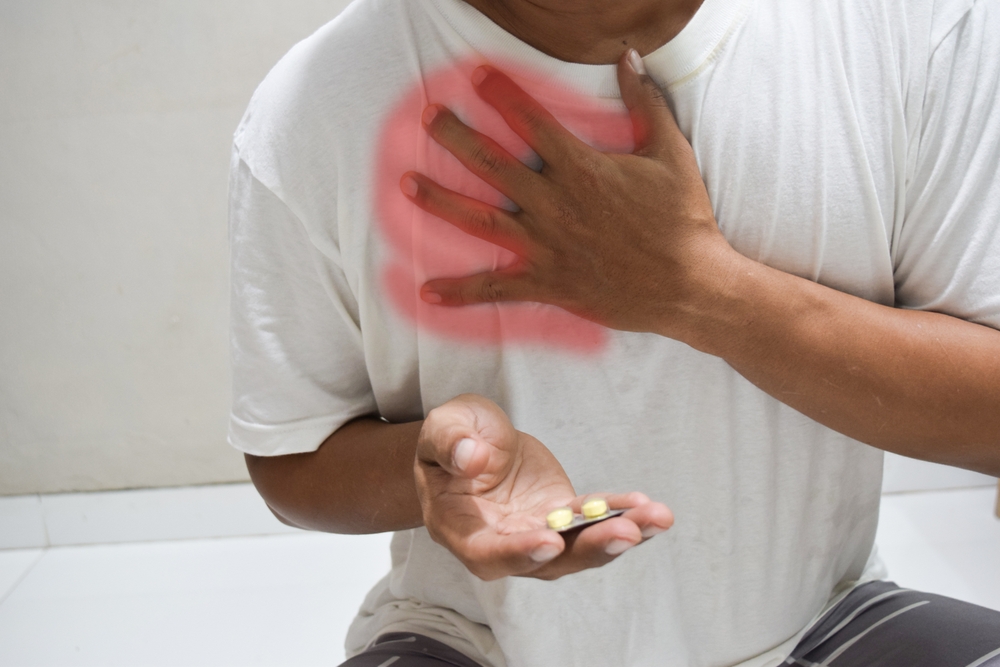 man taking turmeric pill or curcumin herb medicine for gerd, treatmen for heartburn from acid reflux disease