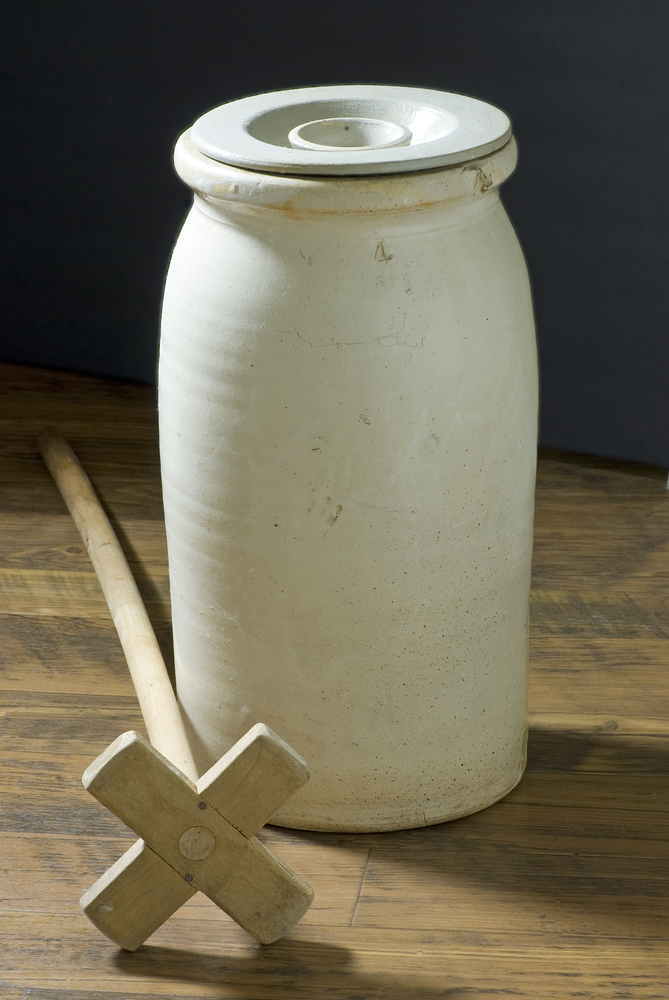 Stoneware Butter Churn and wooden dasher on an old wooden floor with dark background