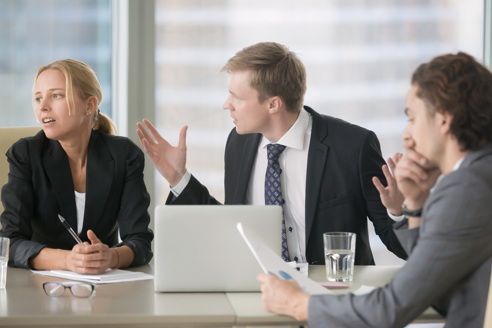 Furious boss scolding young frustrated interns with bad work results. Ineffective office workers sitting at the table and listening to irritated boss yelling with bored and annoyed expressions