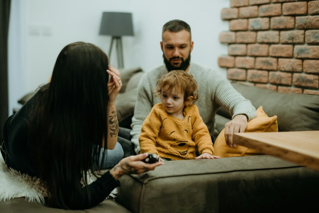 a man sitting on a couch next to a little girl
