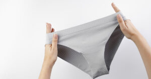 The Complete Guide to Underwear & Your Health: What You Wear Down There Matters woman holding a pair of gray underwear