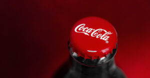 Close up of a glass bottle of Coca-Cola focusing on the red cap.