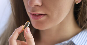 woman taking a supplement in a softgel capsule