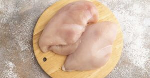 Raw chicken breasts on a circular cutting board