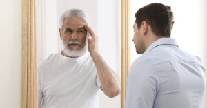 Man looking in mirror seeing older version of himself.