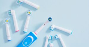 TSA Cracks Down on Unexpected Travel Item: Your Toothbrush electric toothbrush and a lot of different multi-colored replaceable nozzles on blue background top view copy space