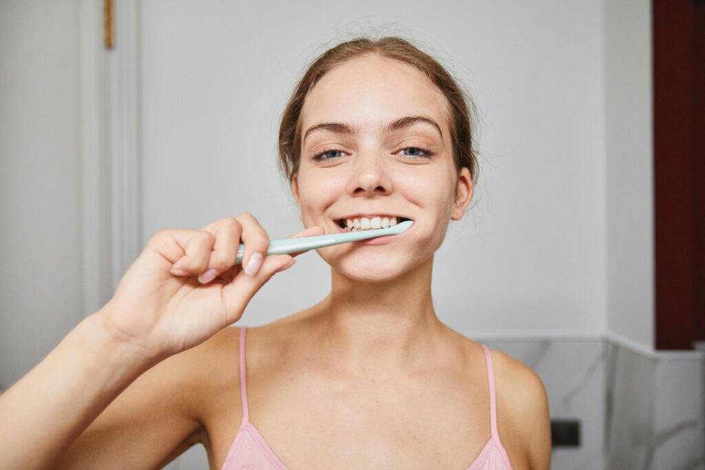 A young lady brushes her teeth to maintain oral hygiene.