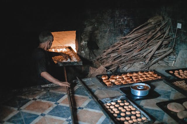 a baker putting dough in an oven